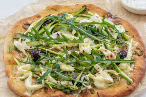 Peeled asparagus on flat bread with other greens