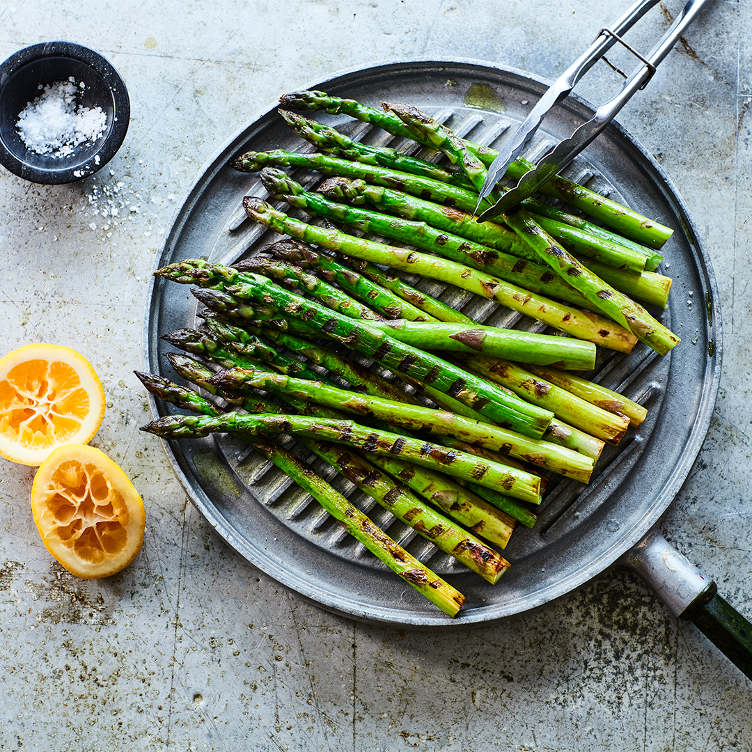 Multiple asparagus being chargrilled in a pan